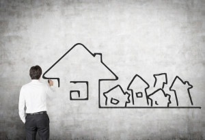 Man drawing houses on white board.